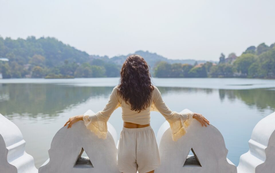 Traveler enjoying the view over Kandy Lake with surrounding hills, capturing a serene moment in kandy travel.